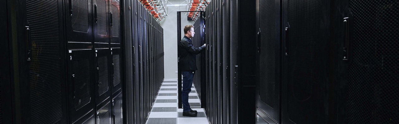 Man standing next to an open data centre cabinet