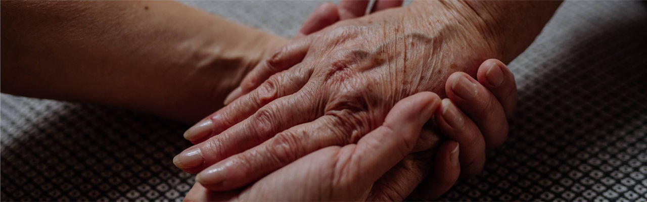 Close-up of adult woman holding her senior mother's hand