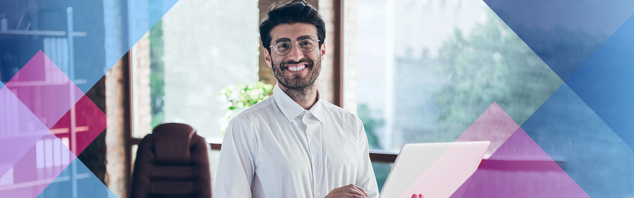 A smiling man holding a laptop