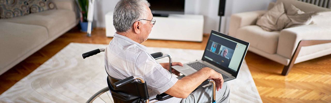 Man with a disability sitting in a wheelchair using a laptop 