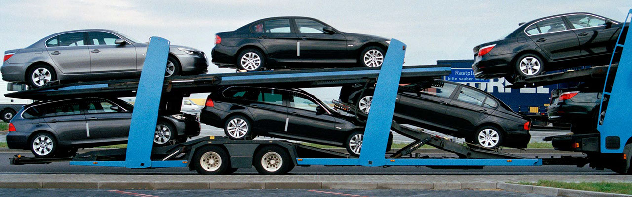 Cars being transported on the back of a blue truck