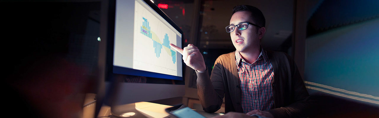 Man wearing glasses reviewing customer analytics on a screen