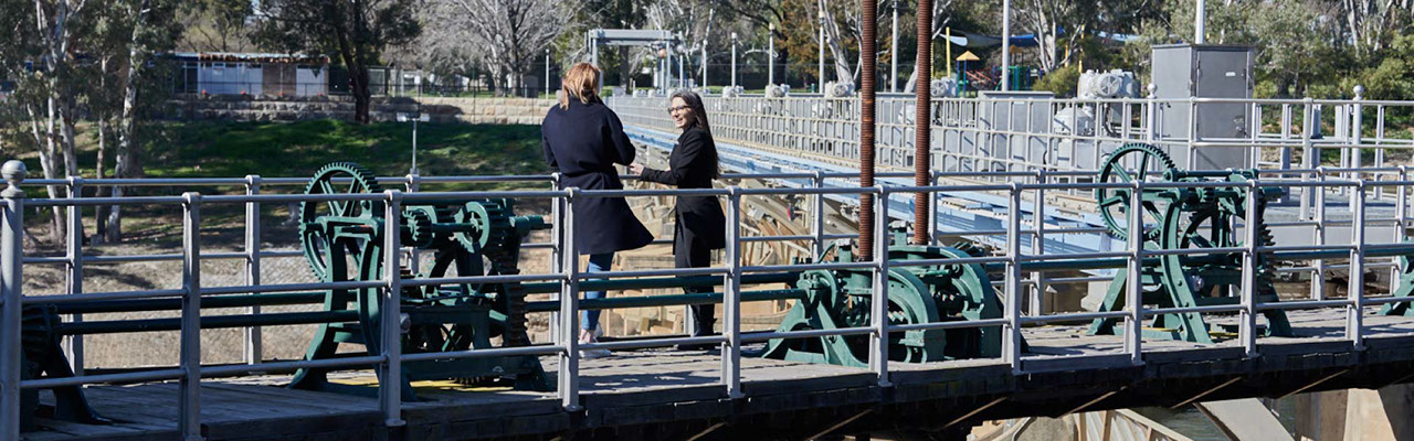 Two women standing on an industrial bridge talking
