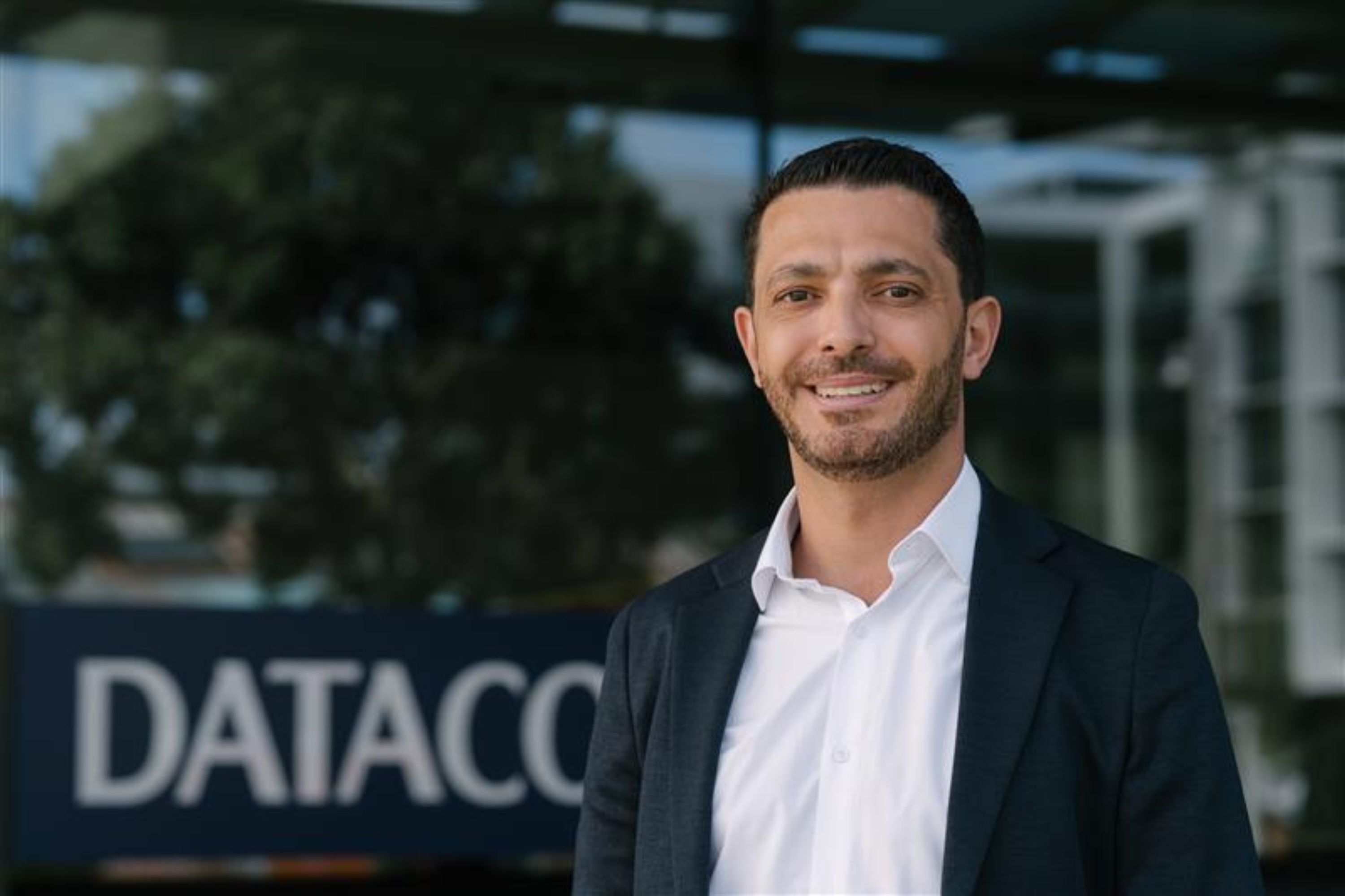 Datacom's Elias in front of Datacom sign