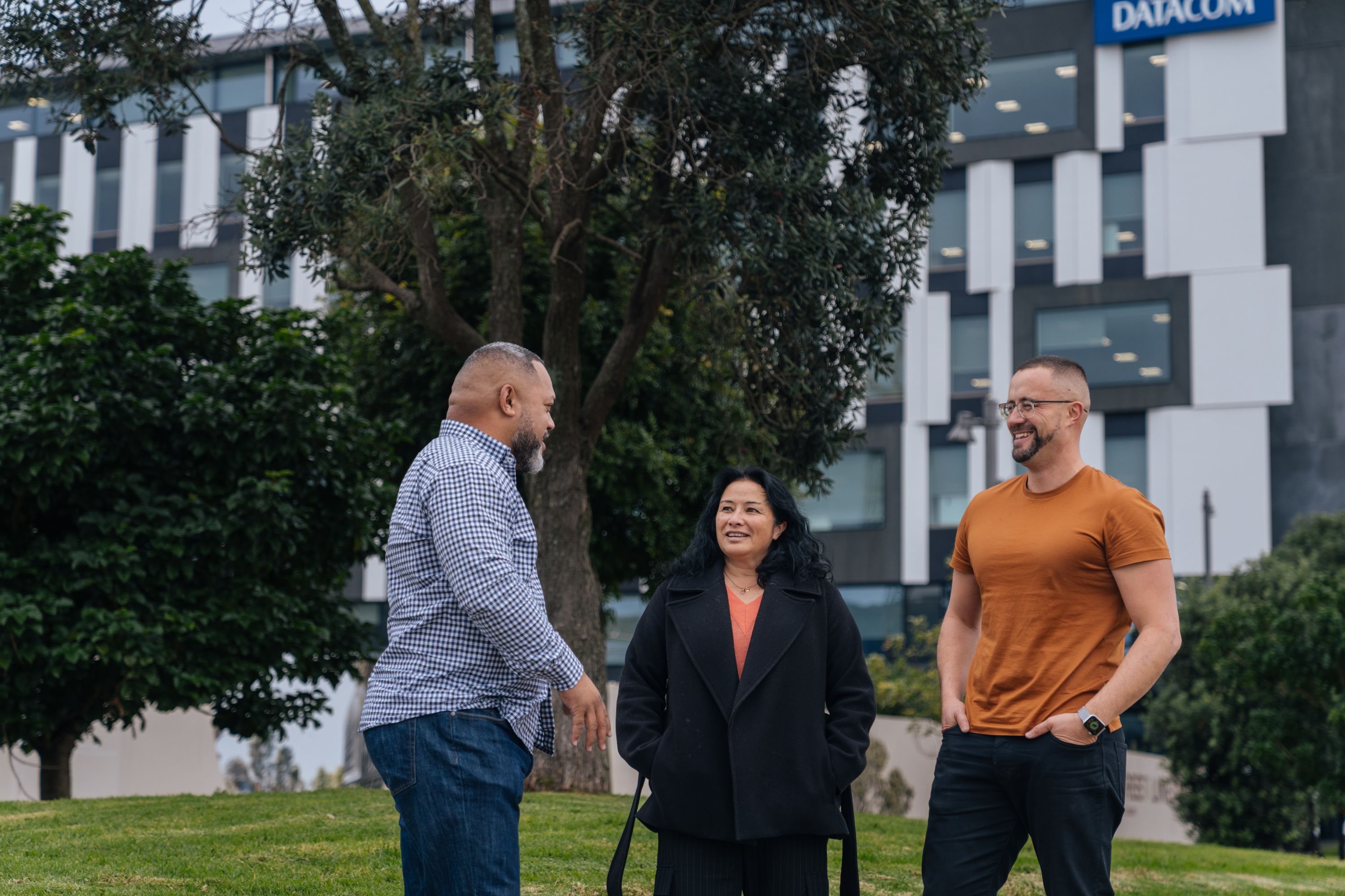 Photo of Amato Funaki, Linda Te Maipi, and James David talking outside the Datacom office