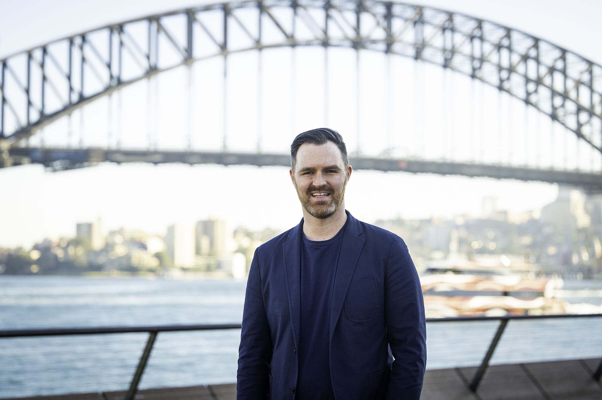 Photo of William Clancy in front of the Sydney harbour bridge