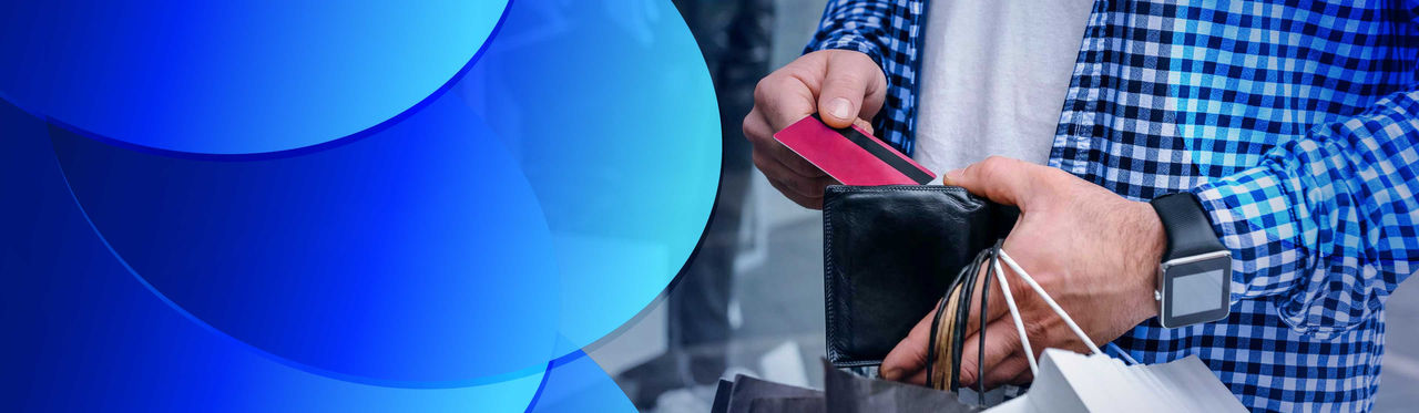 A man sliding a credit card into his wallet while holding shopping bags