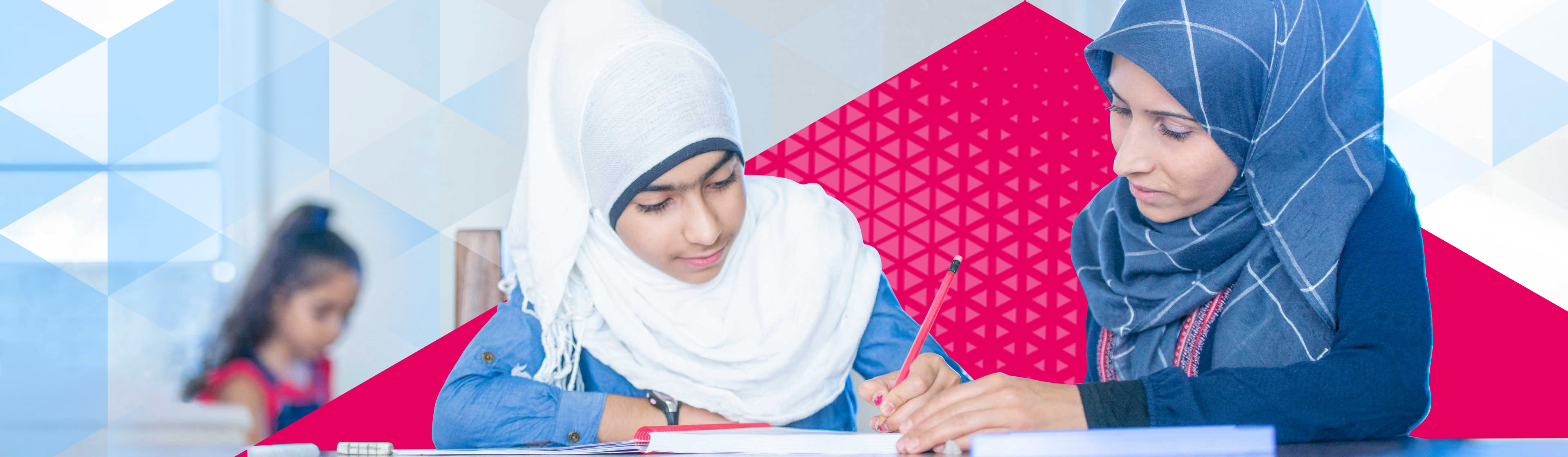 Child wearing a hijab writing in a notebook