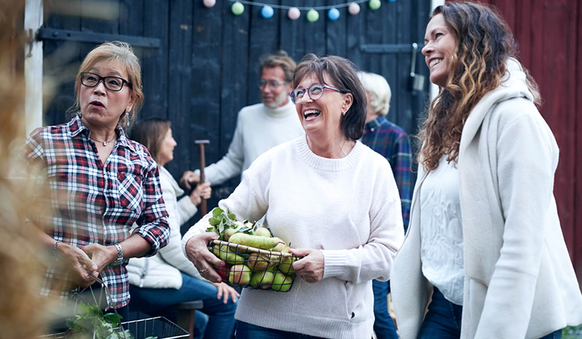 Cheerful women holding baskets of fresh produce among friends 