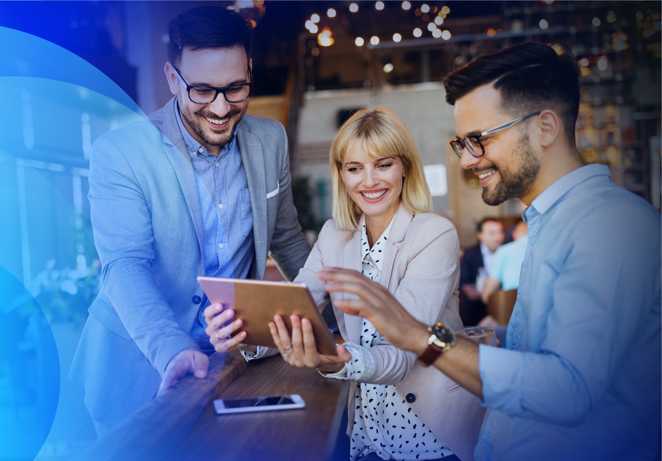 Three smiling employees looking at a tablet