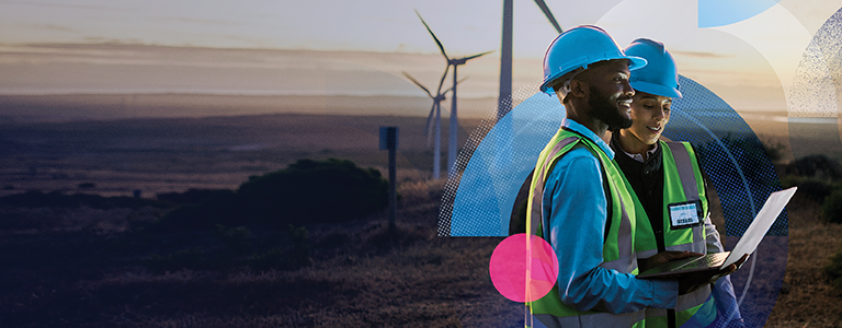 A man and woman looking at a laptop standing in a wind farm.