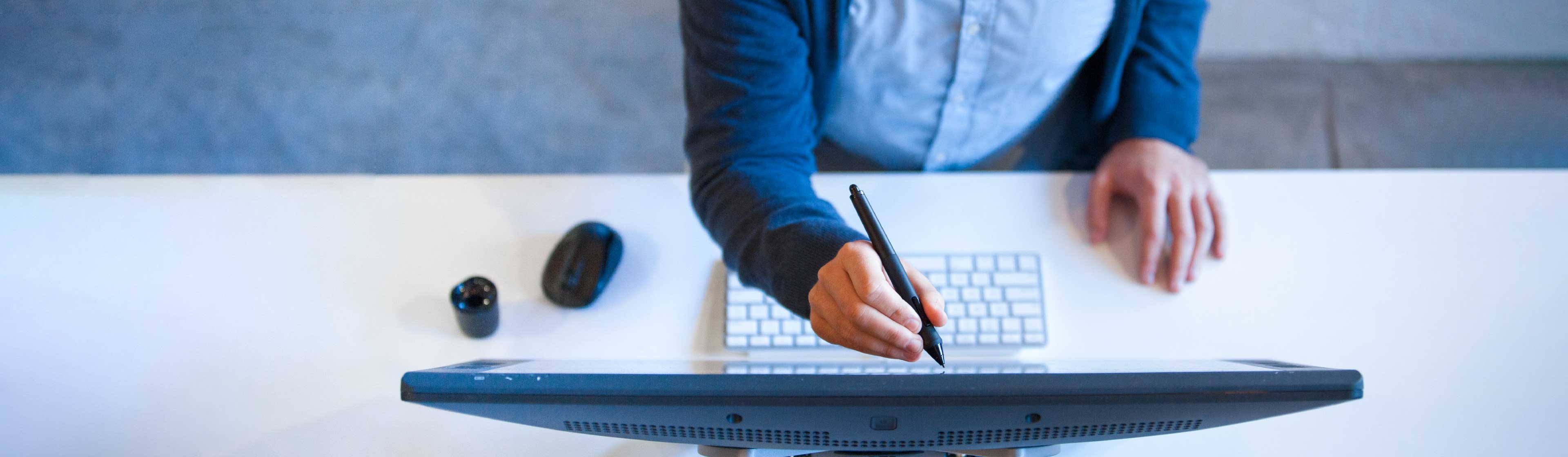 A person in a suit using s stylus to write on a monitor