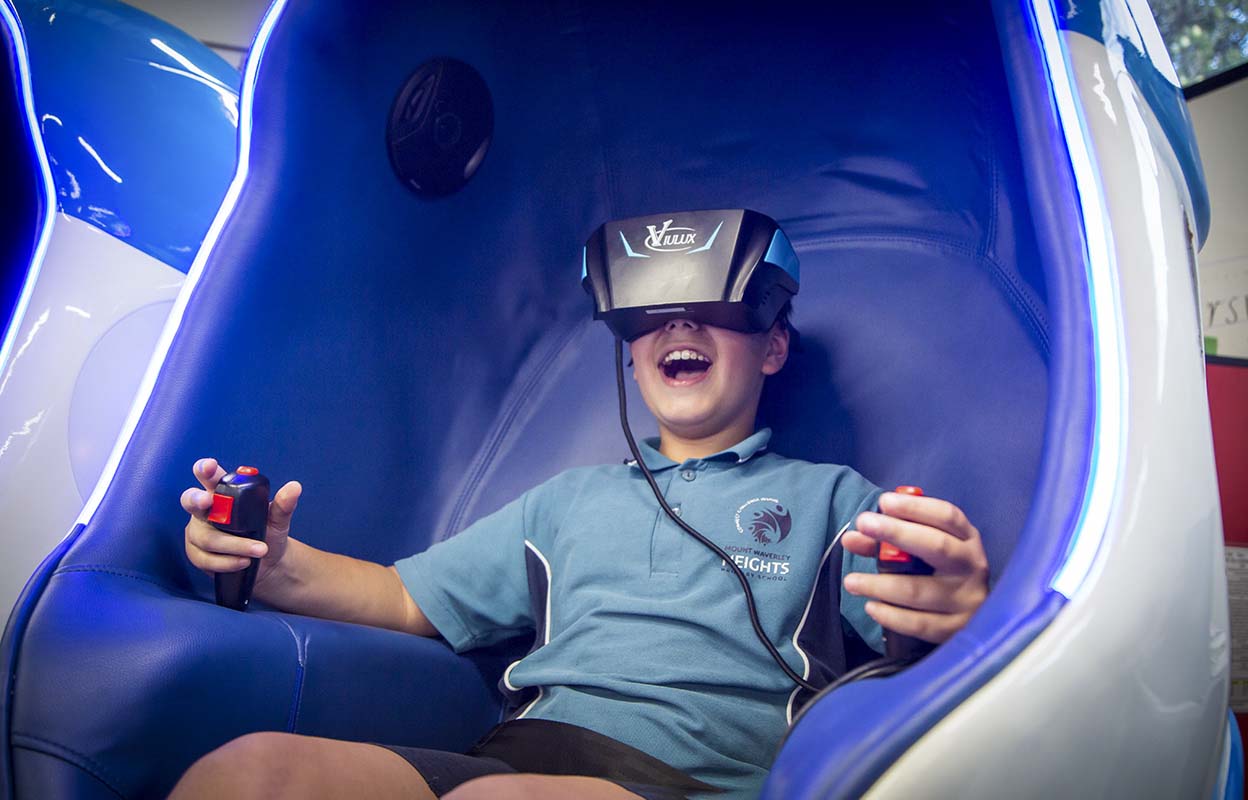 Smiling young student sitting in a VR booth wearing a VR headset