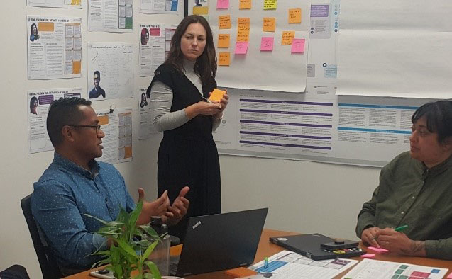 two people talking in front of a white board