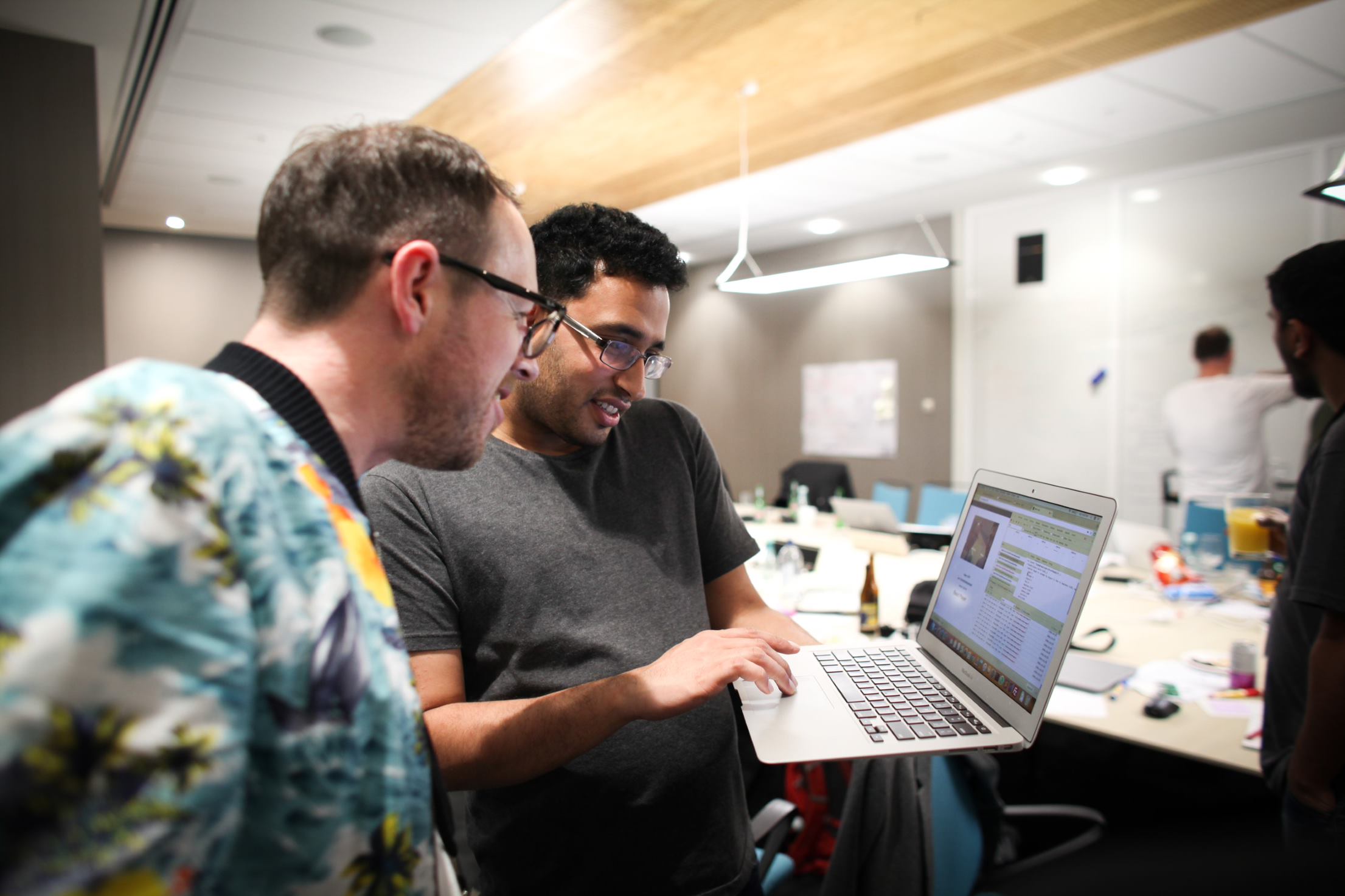 Two tech experts reviewing code on a laptop