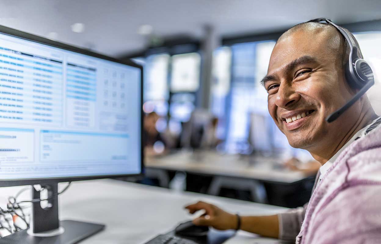 Portrait of smiling customer service representative talking on microphone in call centre.