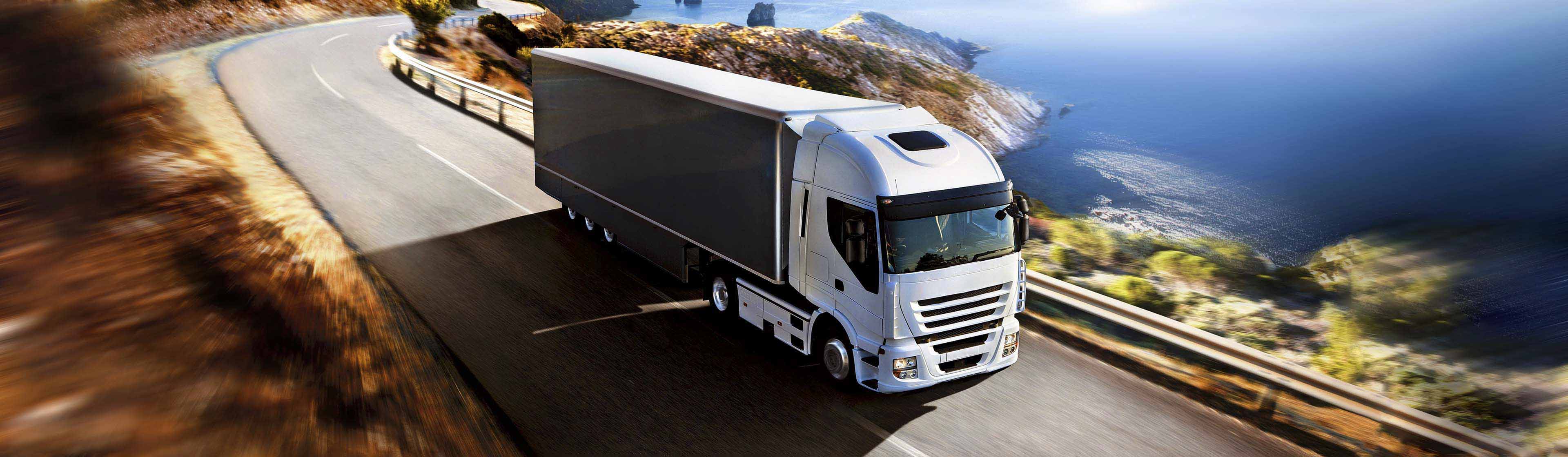A truck driving on a scenic road overlooking the ocean