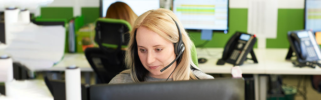 A female customer service representative on a call at her desk