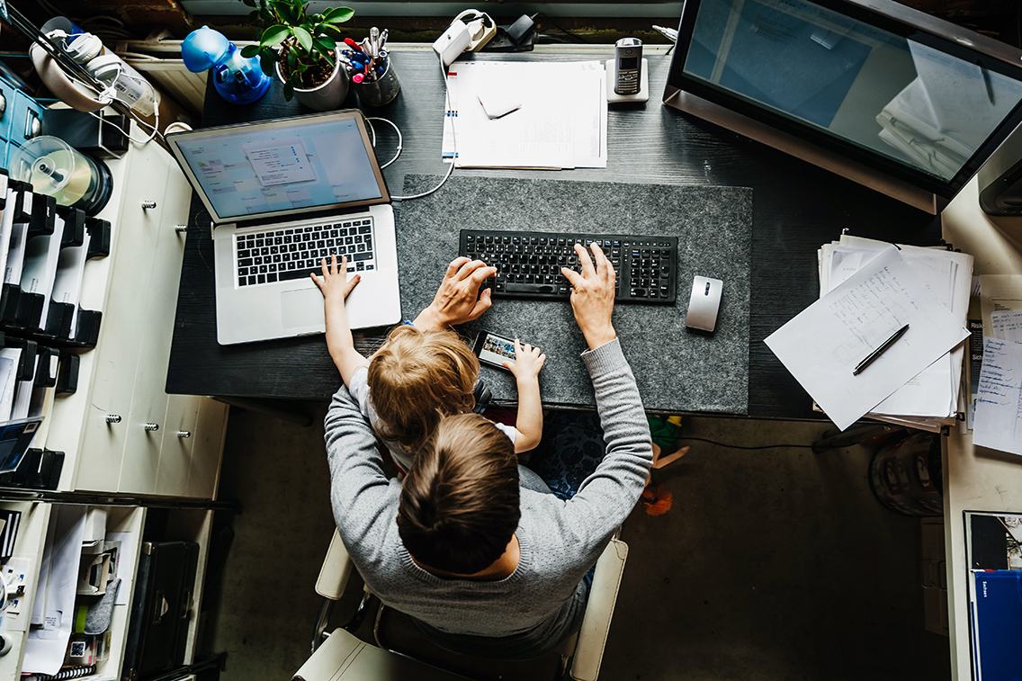 woman working at desk with child on lap