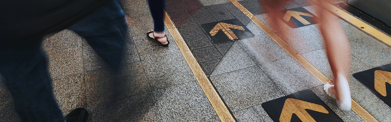 People walking with arrows on the footpath marking the way forward
