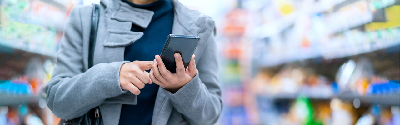 Lady in a supermarket using a phone for digital shopping