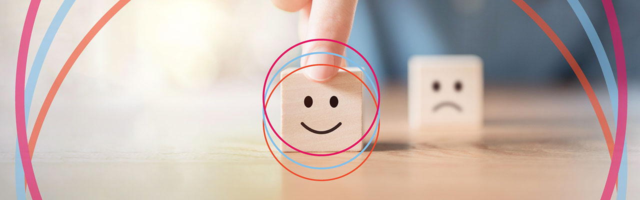 A person's hand touching cubes with positive and negative smiley faces on them