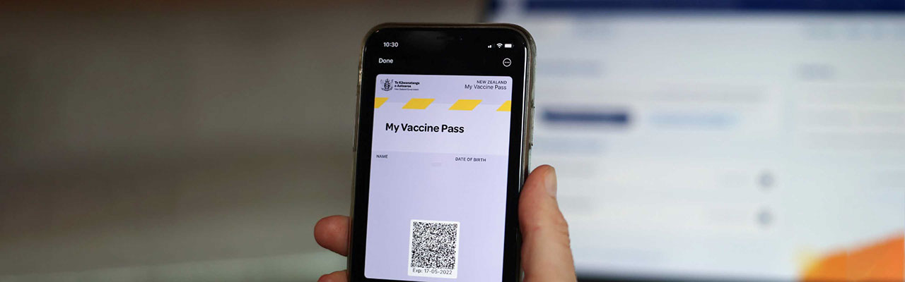 Picture of a hand holding a phone displaying a Covid-19 "My Vaccine Pass".