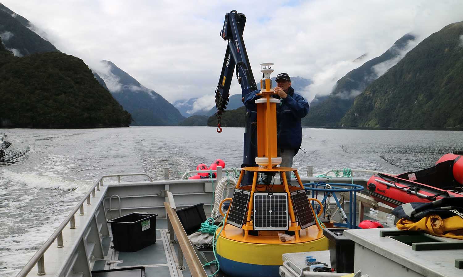 Man preparing a research buoy on a boat in Doubtful Sound, New Zealand